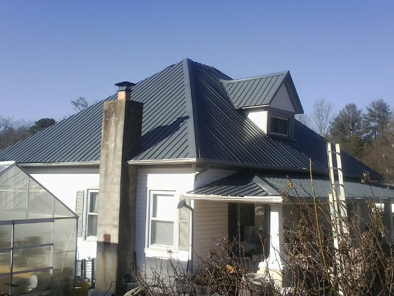 Dark blue standing seam metal roof on a white farmhouse with dormer — Slate & Tile Roof Repair by Roofing Brothers in New Braintree