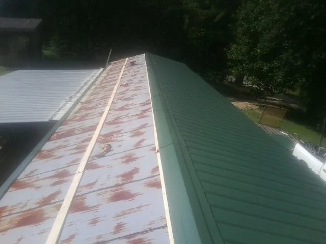 Old rusted panels beside newly installed green metal roofing — Wind Damage Roof Repair by Roofing Brothers in New Braintree