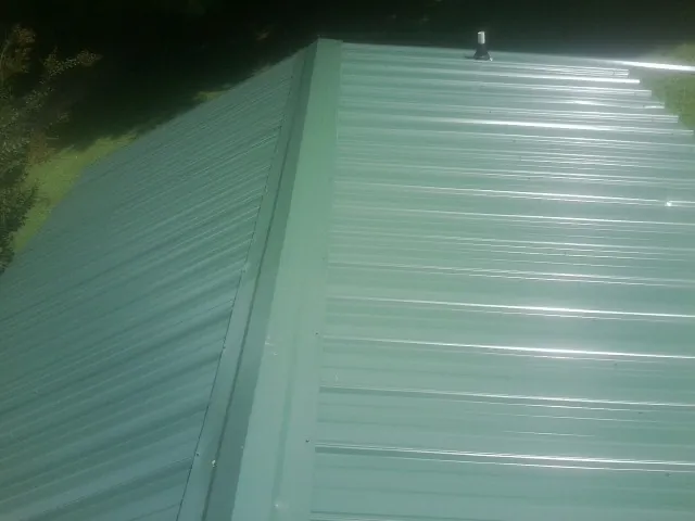 New green metal panels meeting at the ridge of a roof — Flat Roof Repair work by our crew in New Braintree