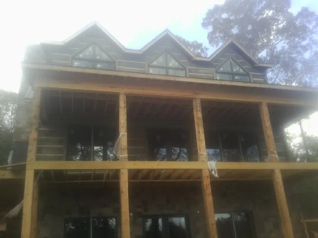 Dormers and porch framing on a large log home under construction — Roof Coating work by our crew in New Braintree