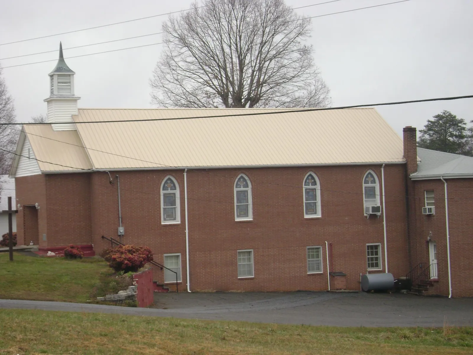 New tan metal roof on a brick church with a white steeple in New Braintree