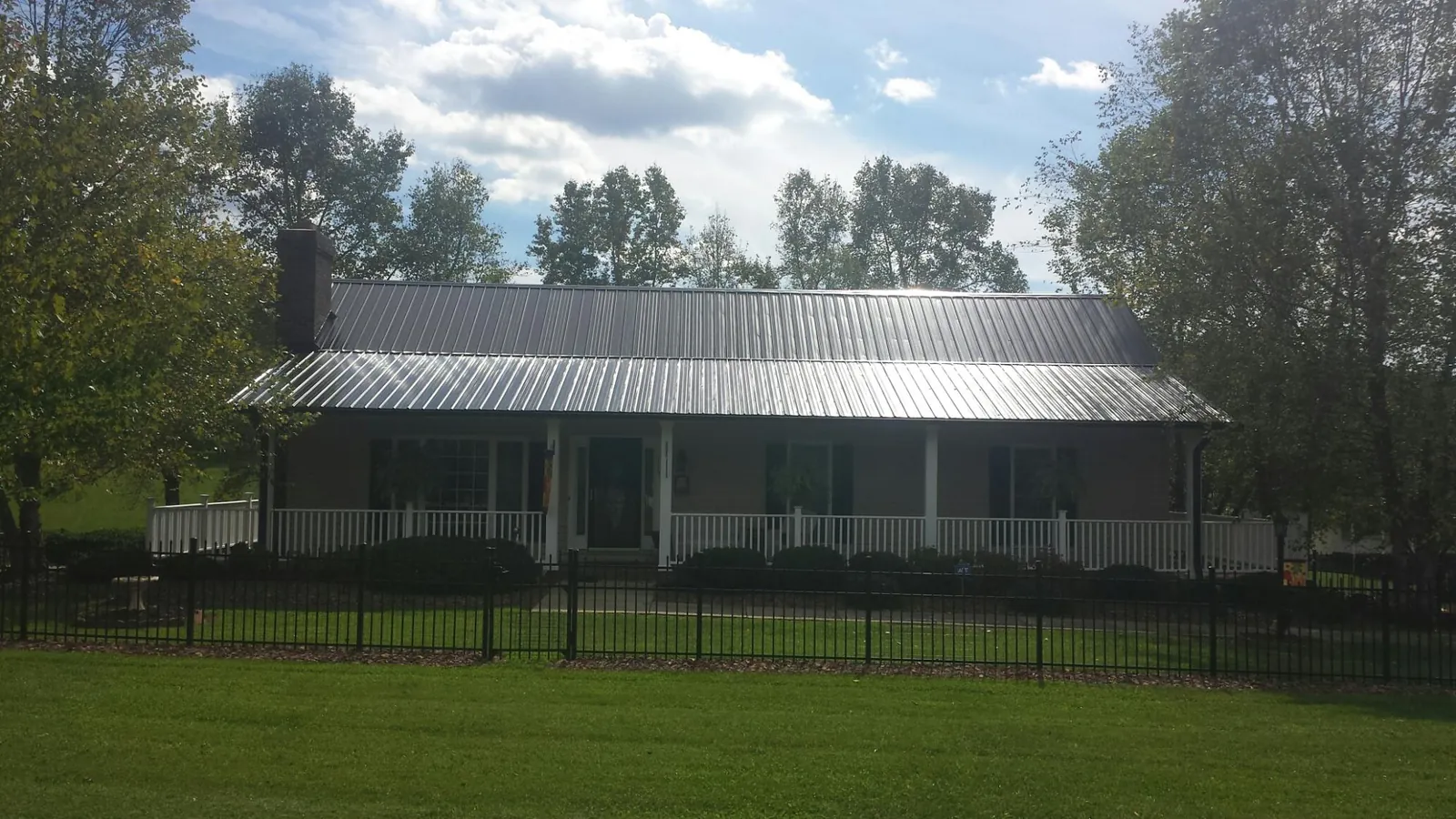 Gray metal roof on a brick ranch with a full width front porch — Gutter Guard Installation work by our crew in New Braintree