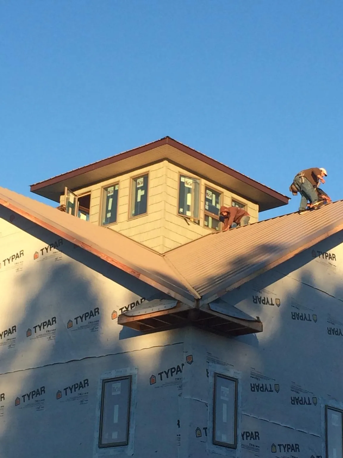 Roofers working around a rooftop cupola on a new metal roof at sunset — Roof Waterproofing in New Braintree by Roofing Brothers
